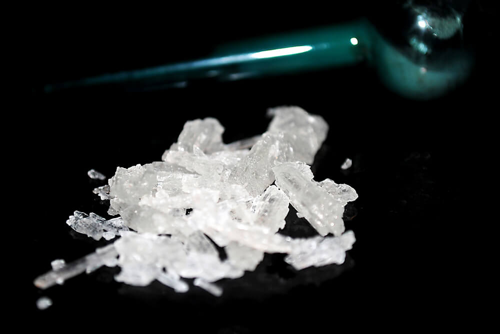 small pile of crystal meth next in front of a glass pipe